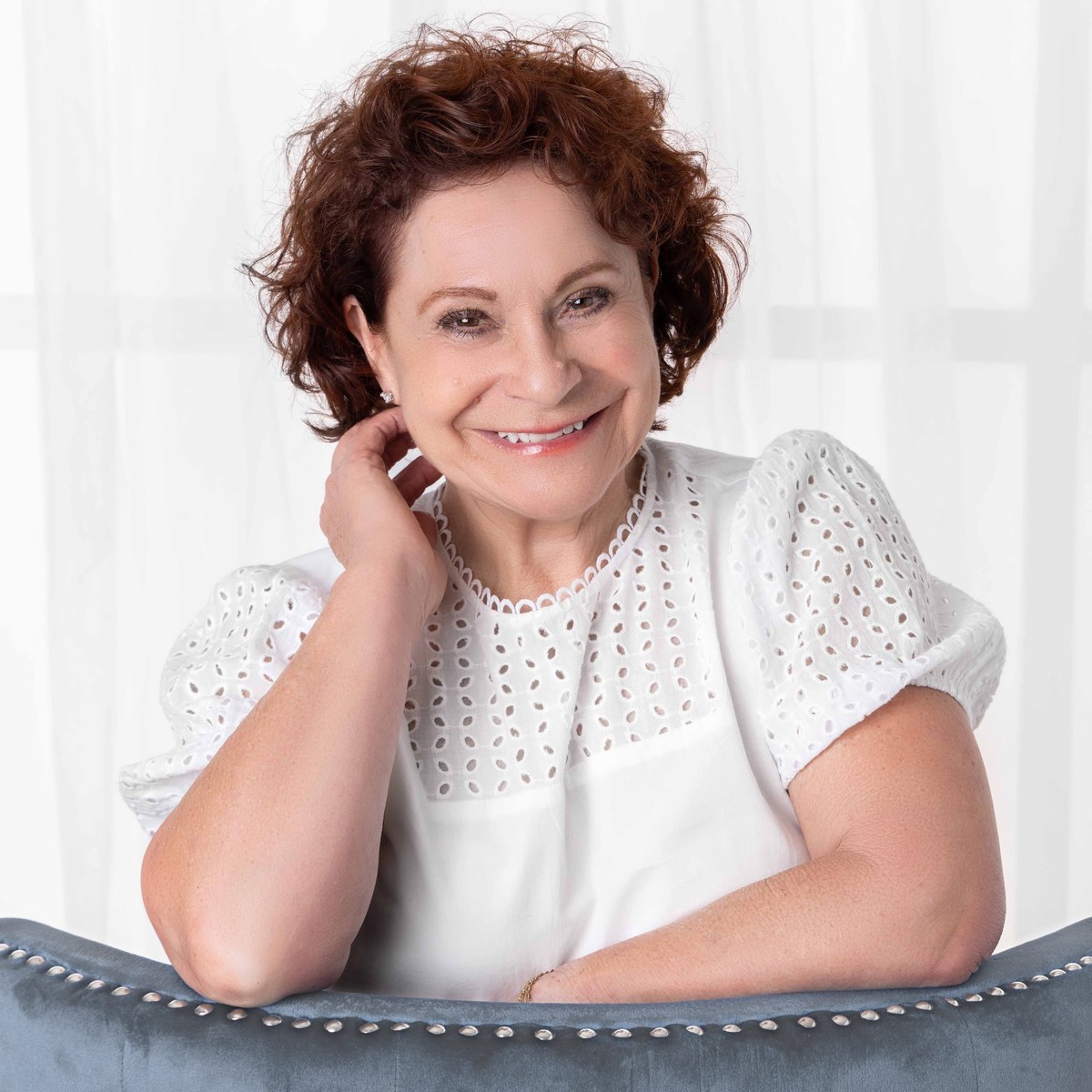 Susan East, resting her arms on the back of a chair