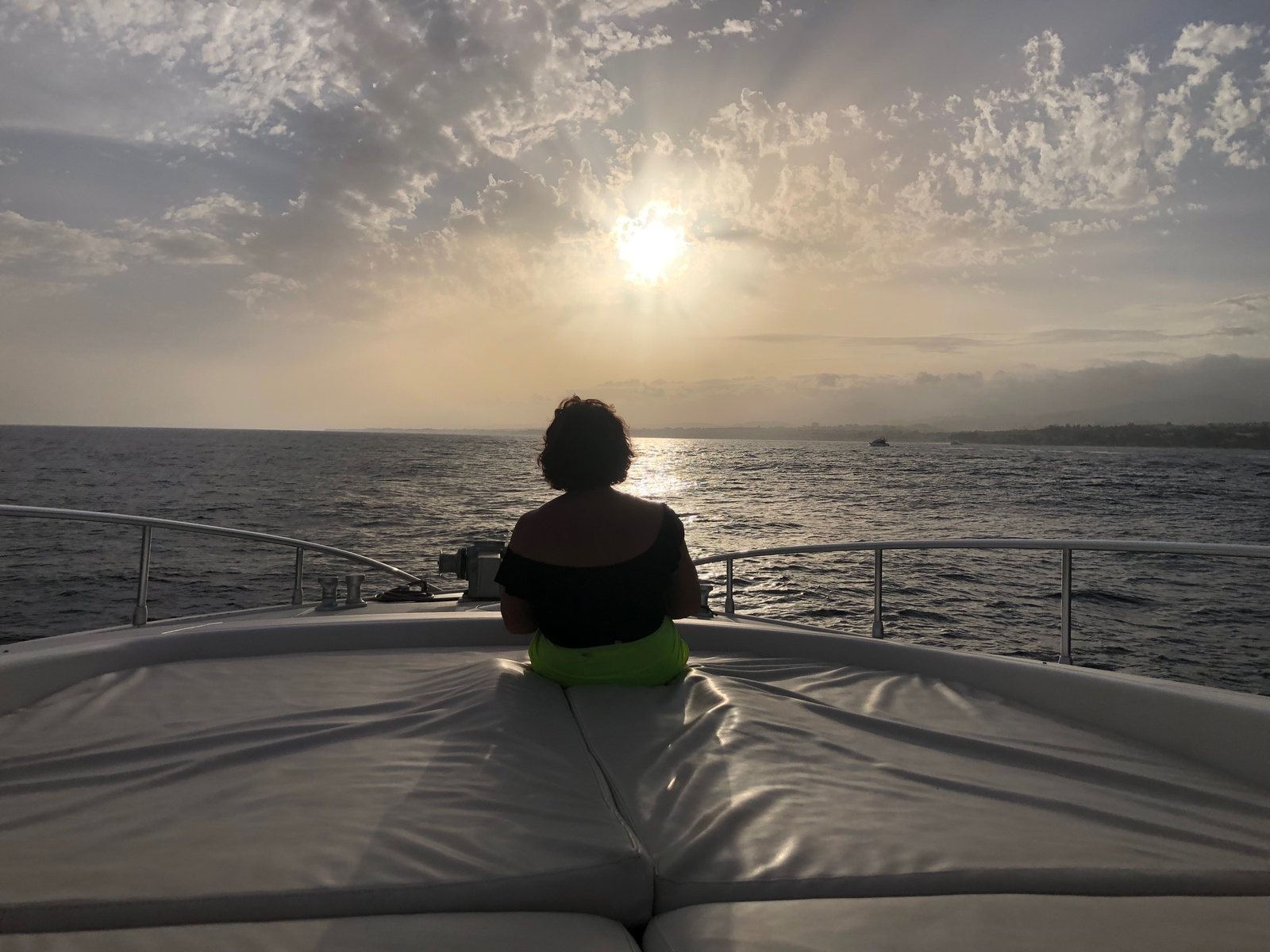 Susan East seated on the bow of a yacht at sunset, looking out over the sea